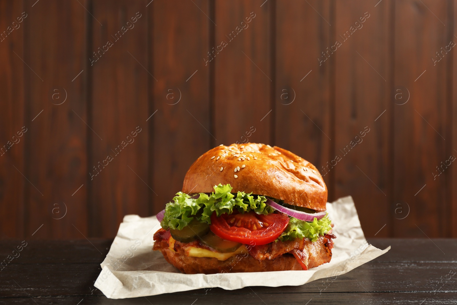 Photo of Delicious burger with bacon on table against blurred background. Space for text