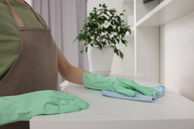 Woman with microfiber cloth cleaning white table in room, closeup