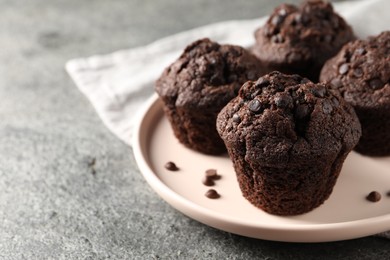 Photo of Delicious chocolate muffins on grey textured table, closeup and space for text