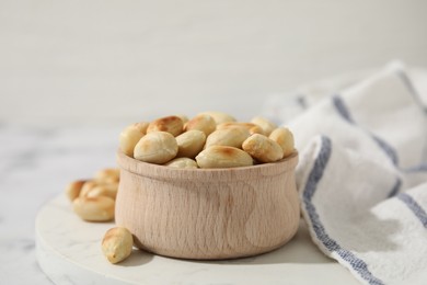 Photo of Roasted peanuts in bowl on white table, closeup