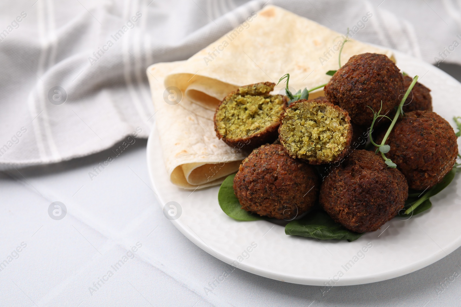 Photo of Delicious falafel balls, herbs and lavash on white table, space for text