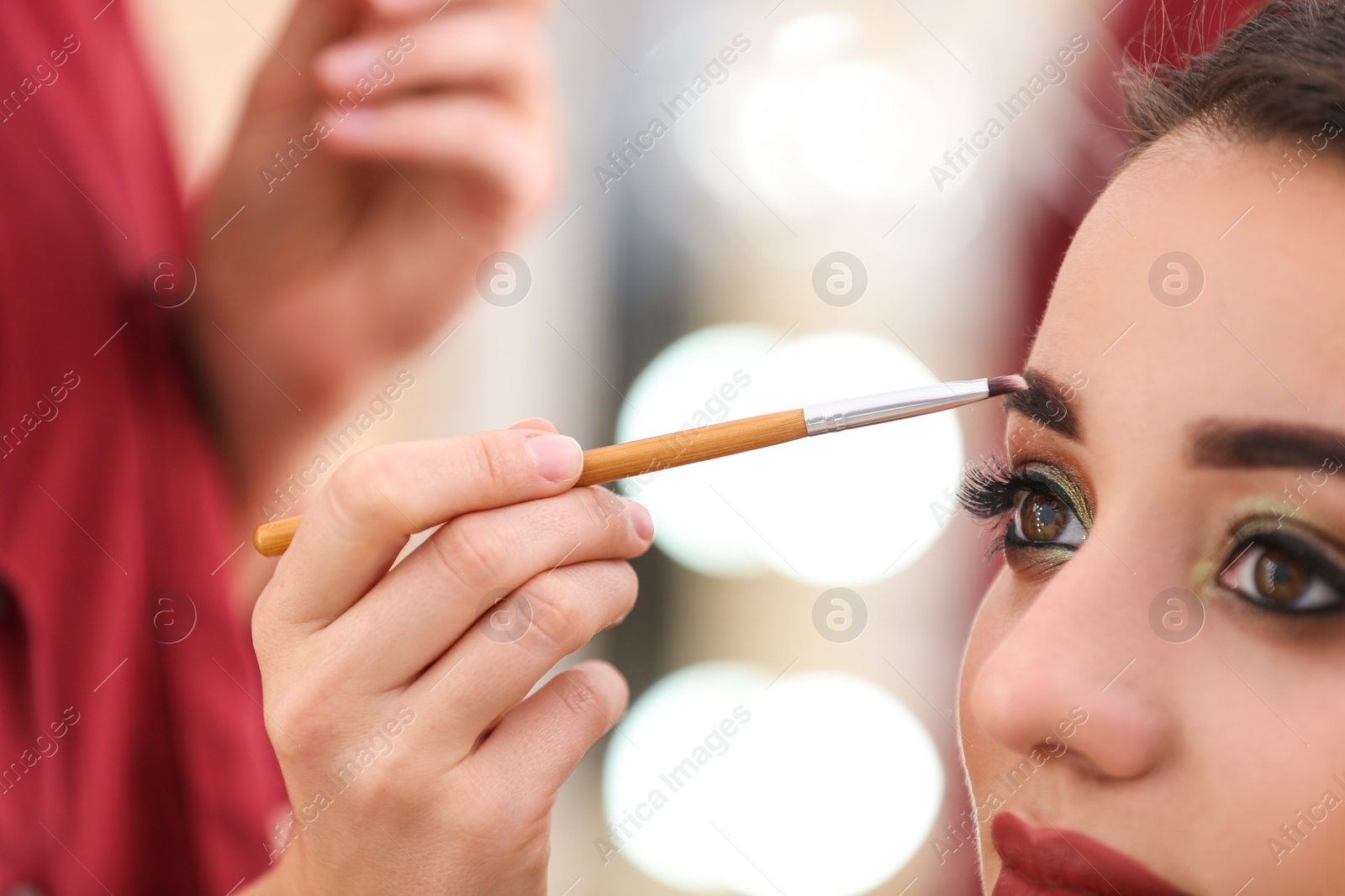 Photo of Professional visage artist applying makeup on woman's face in salon, closeup