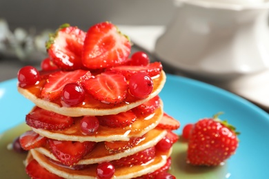 Photo of Tasty pancakes with berries and honey on plate, closeup