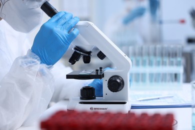 Photo of Scientist working with samples and microscope in laboratory, closeup