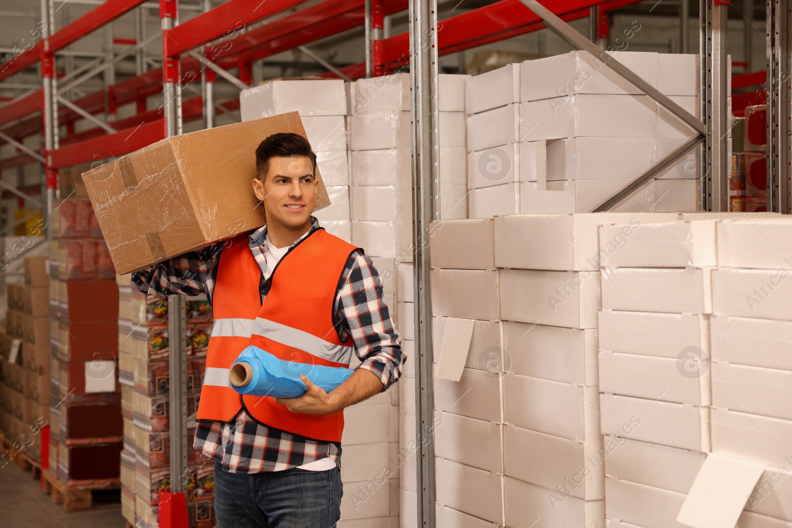 Photo of Worker with roll of stretch film and wrapped box in warehouse