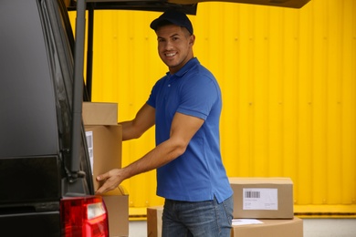 Photo of Courier taking parcel from delivery van outdoors