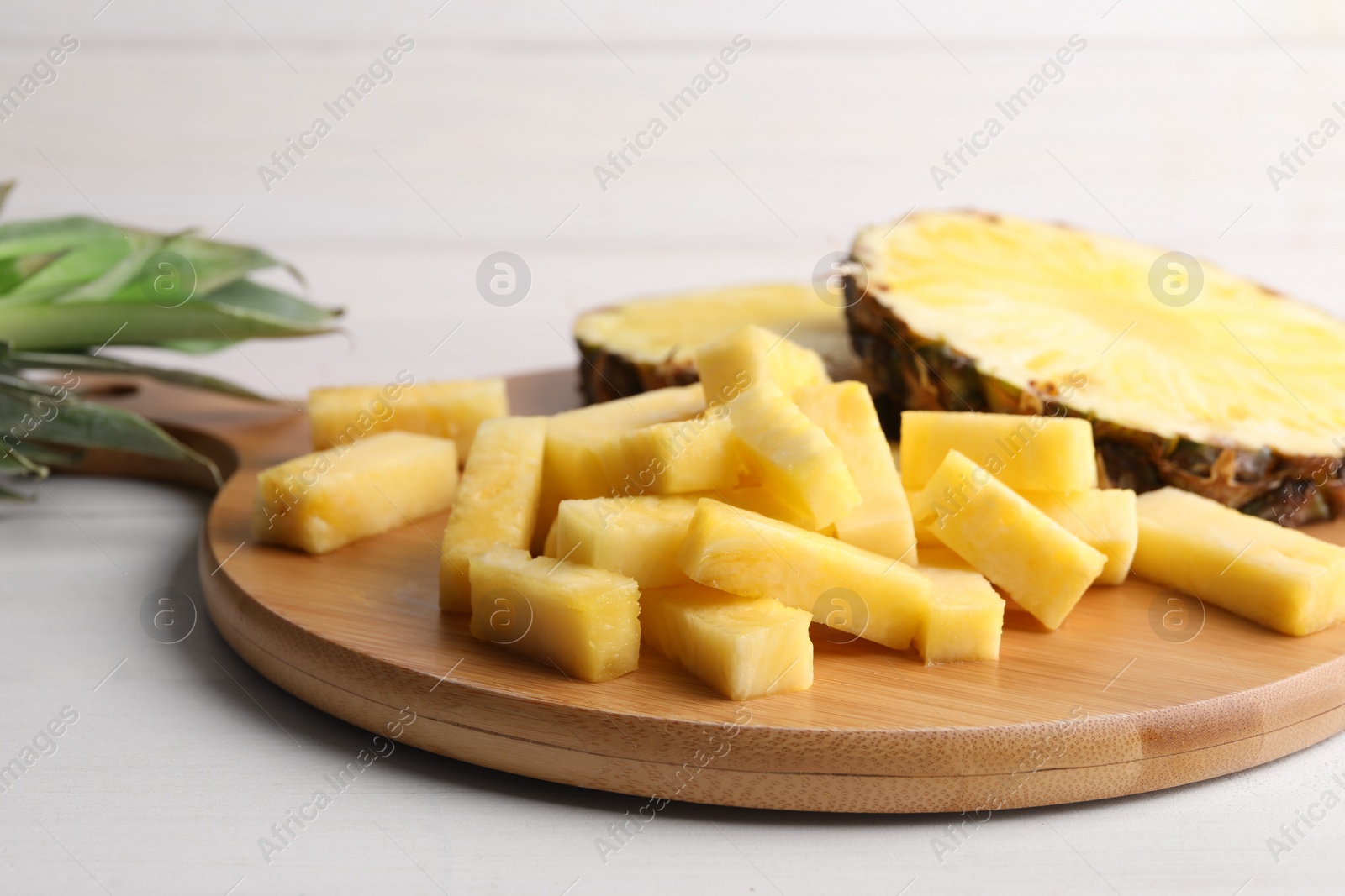 Photo of Pieces of tasty ripe pineapple on white wooden table, closeup