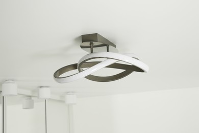 Stylish lamp on white ceiling. Space for text