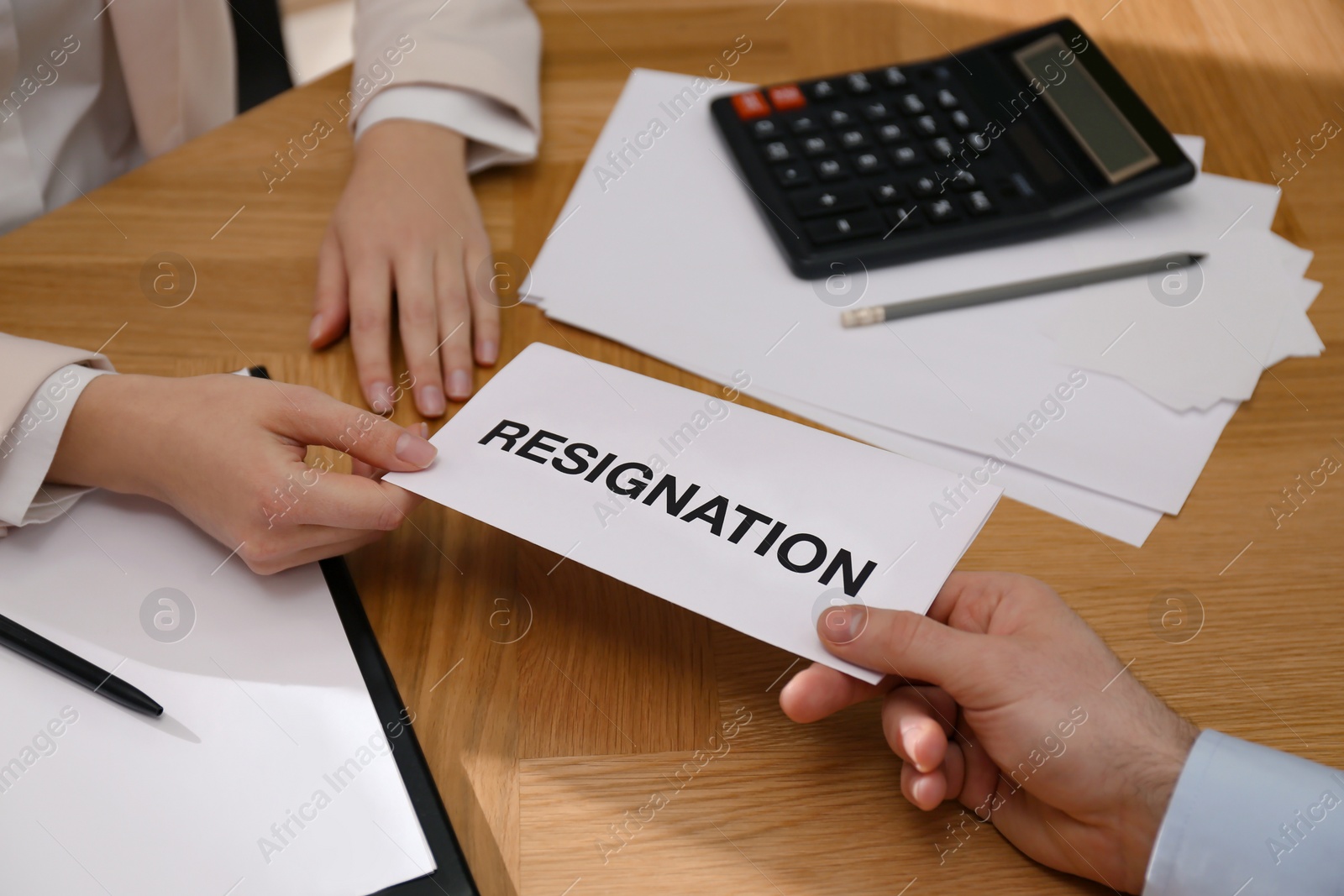 Photo of Employee giving resignation letter to boss in office, closeup