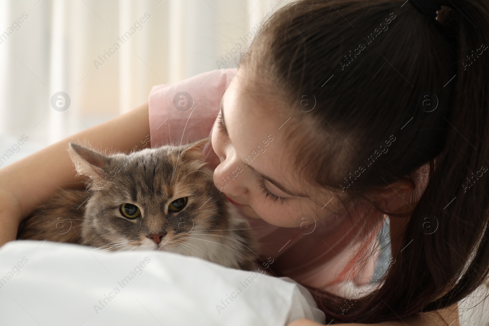 Photo of Cute little girl with cat lying on bed at home. First pet