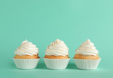 Photo of Delicious cupcakes with white cream on turquoise background. Space for text