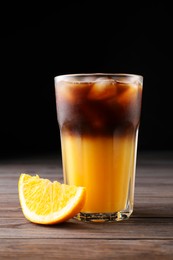 Photo of Tasty refreshing drink with coffee and orange juice on wooden table against dark background