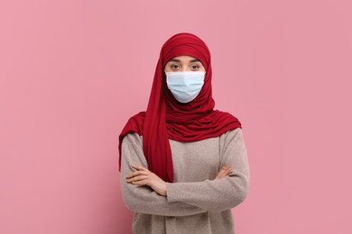 Photo of Muslim woman in hijab and medical mask on pink background