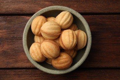 Photo of Delicious nut shaped cookies with boiled condensed milk in bowl on wooden table, top view