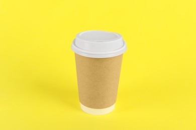 Photo of Paper cup with plastic lid on yellow background. Coffee to go