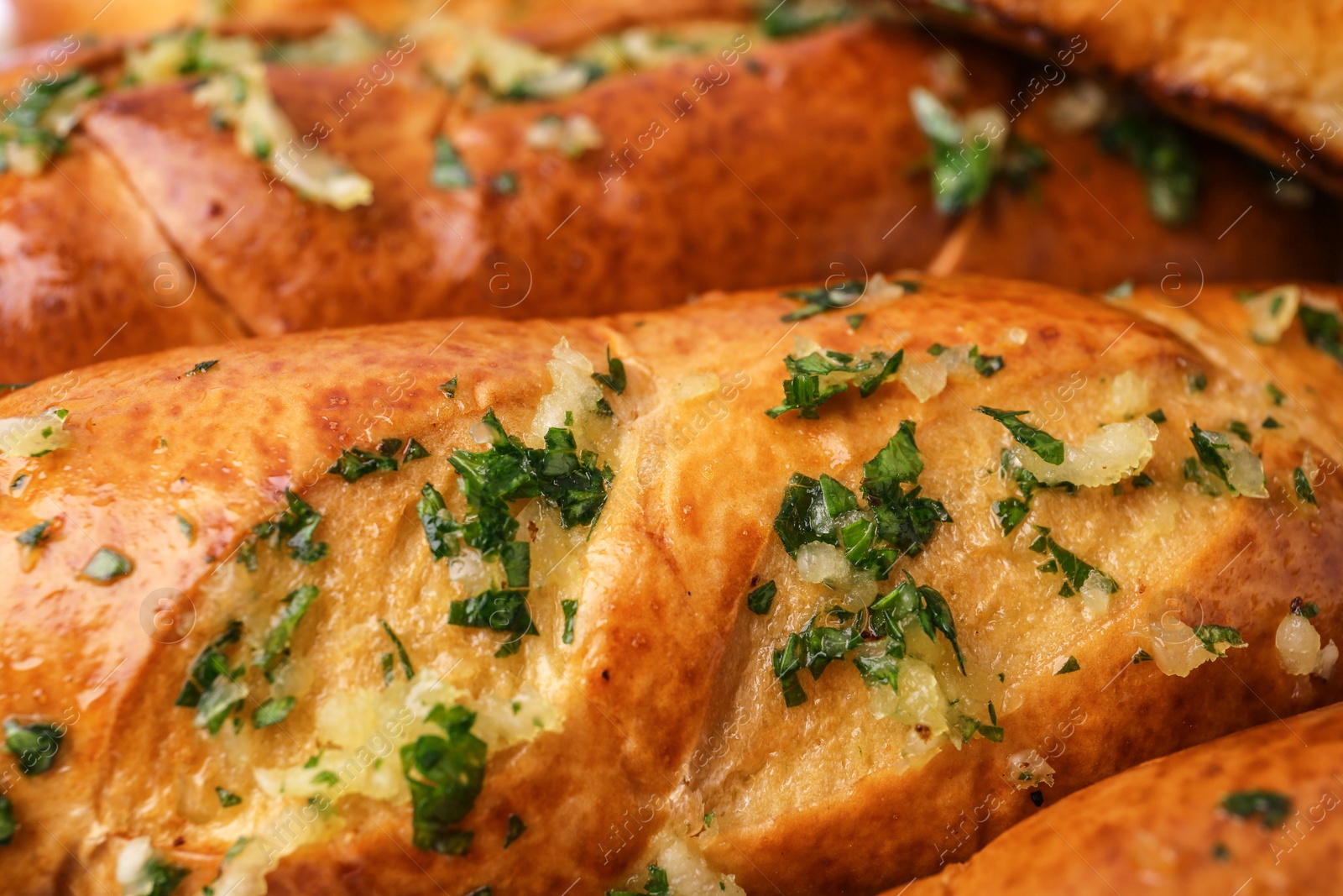 Photo of Bread loaves with garlic and herbs as background, closeup