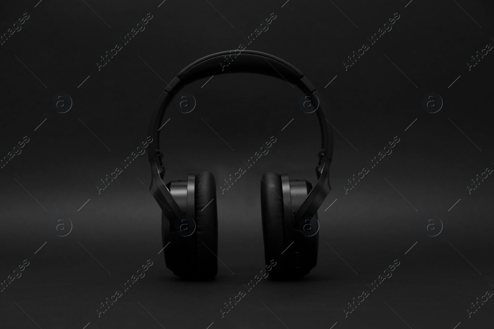 Photo of Stylish modern wireless headphones on dark background