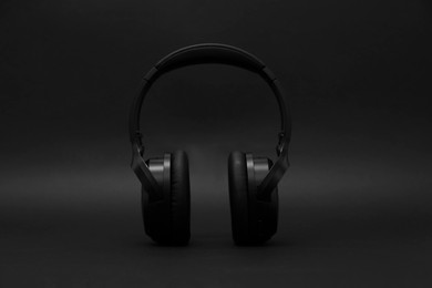Photo of Stylish modern wireless headphones on dark background