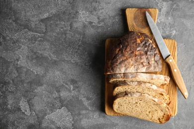 Photo of Board with bread and knife on grey background, top view. Space for text