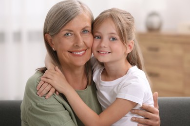 Photo of Happy grandmother hugging her granddaughter at home