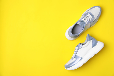 Stylish sneakers on yellow background, flat lay. Space for text