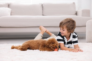 Photo of Little child and cute puppy on carpet at home. Lovely pet