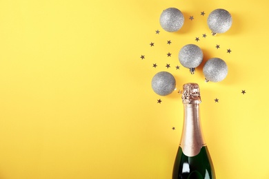 Photo of Christmas composition with bottle of champagne, balls and space for text on color background, top view