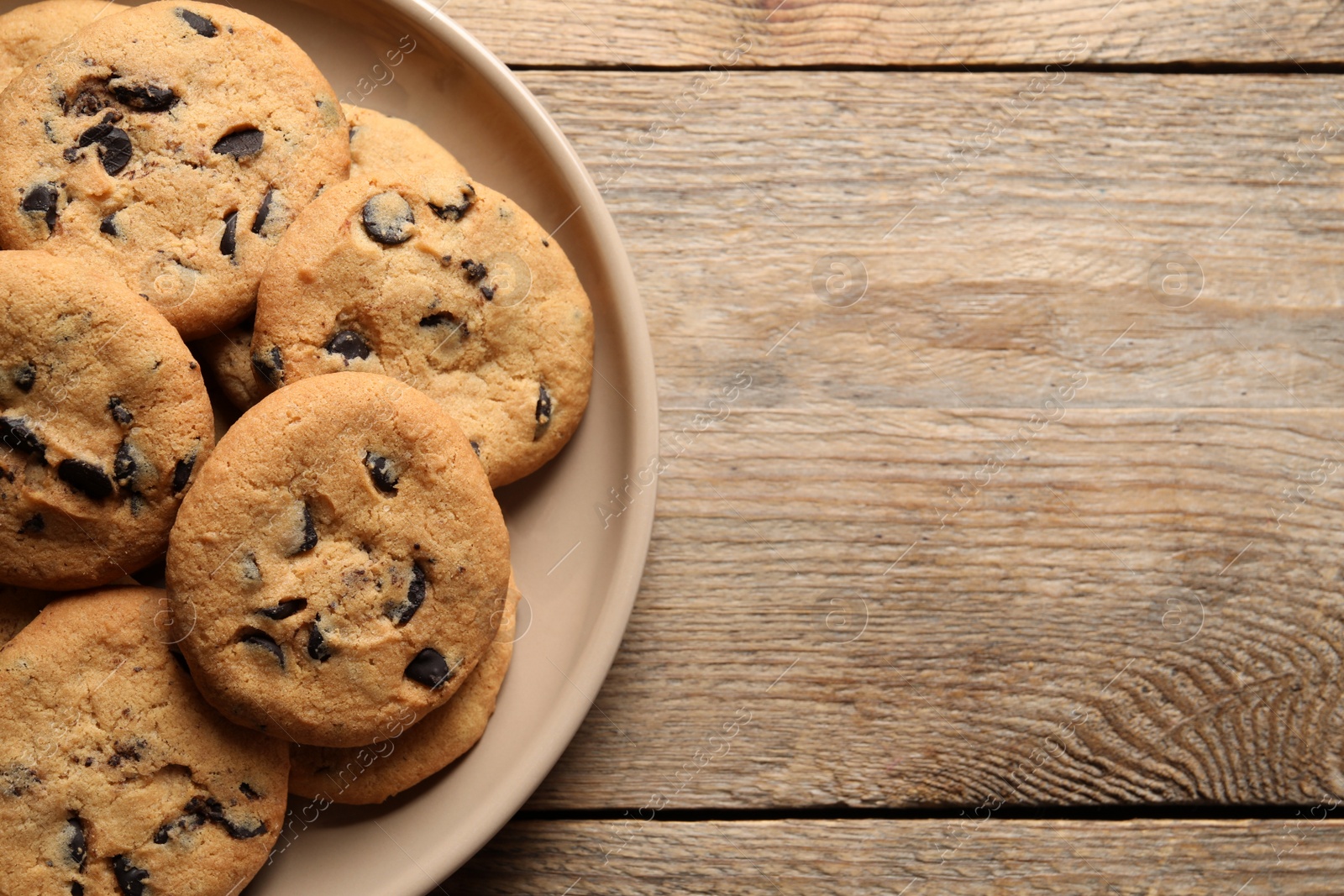 Photo of Delicious chocolate chip cookies on wooden table, top view. Space for text