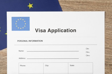 Immigration to Europe. Visa application form and flag on wooden table, top view