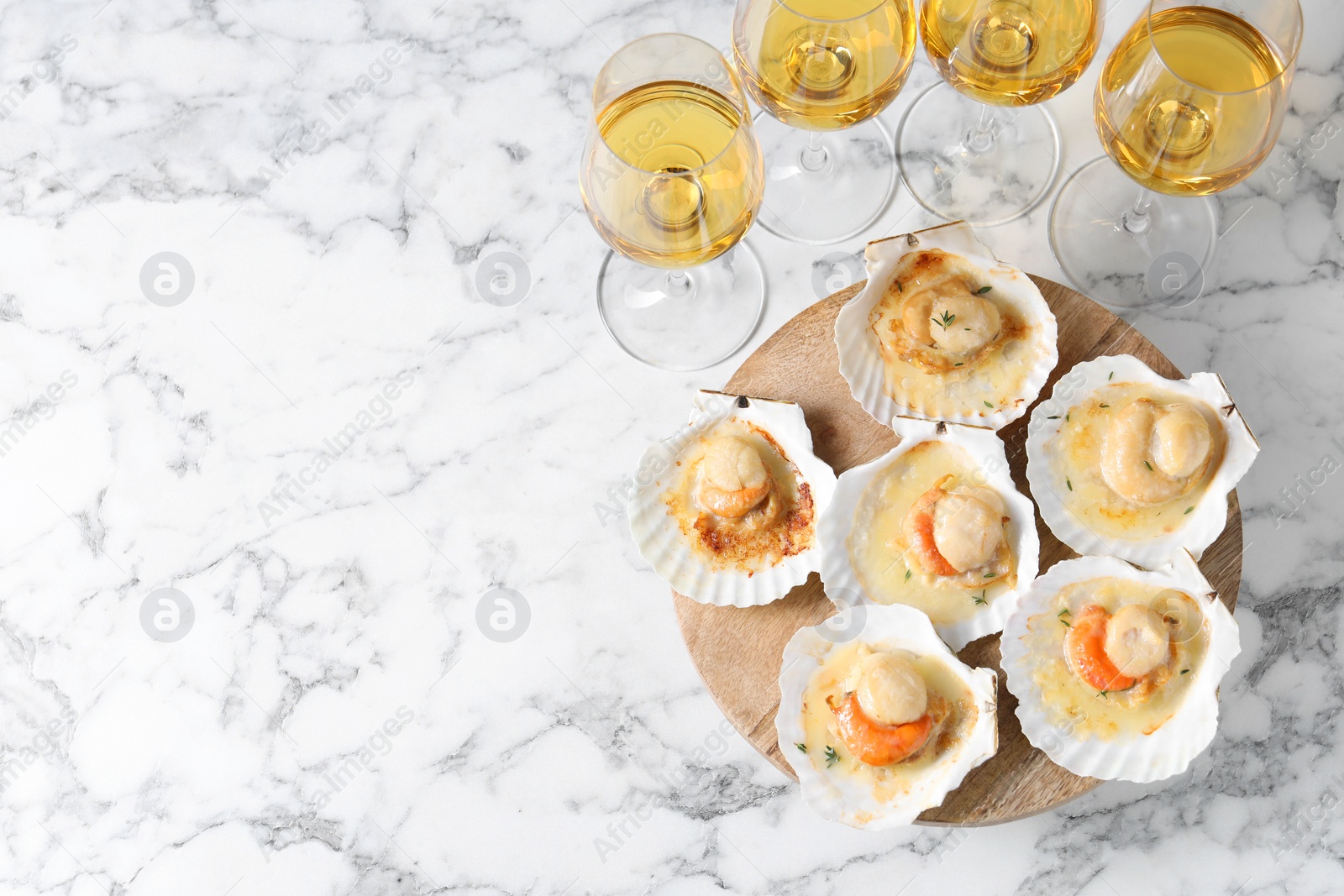 Photo of Fried scallops in shells and wine on white marble table, above view. Space for text