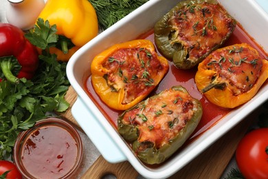 Photo of Tasty stuffed peppers in dish and ingredients on grey table, flat lay