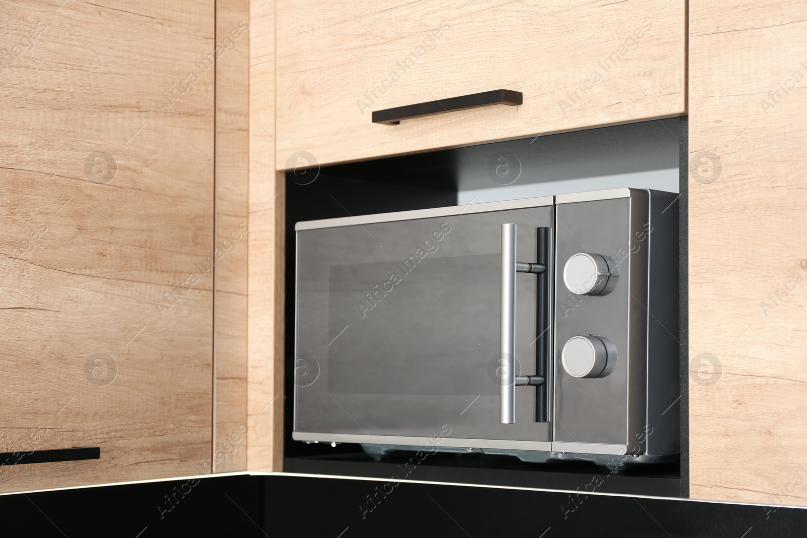 Photo of Modern microwave oven on shelf in kitchen