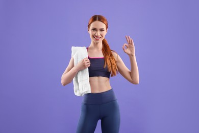 Photo of Woman wearing sportswear with towel on violet background