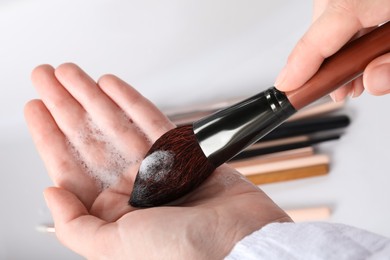 Photo of Woman washing makeup brush with soap, closeup