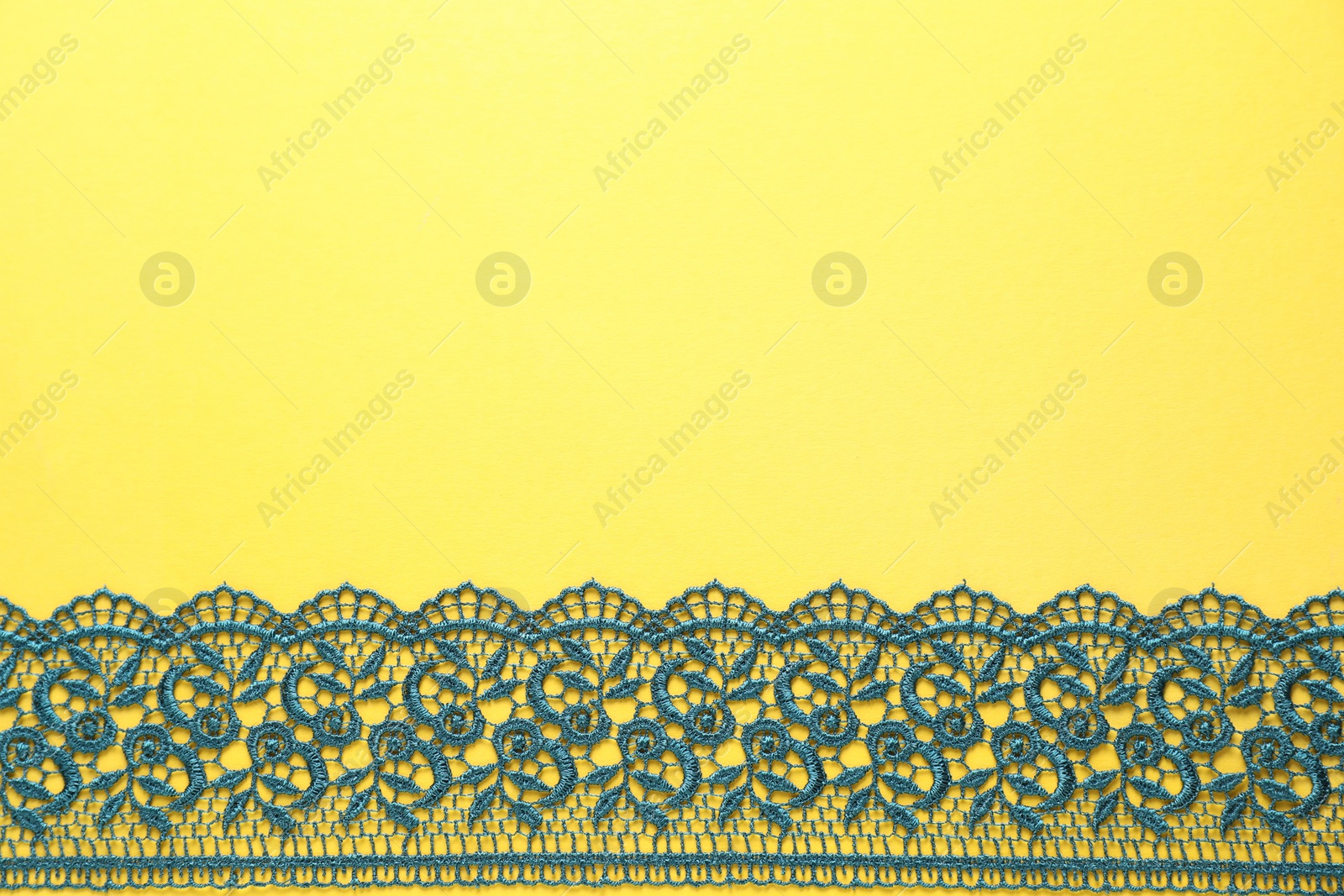 Photo of Green lace on yellow background, top view. Space for text