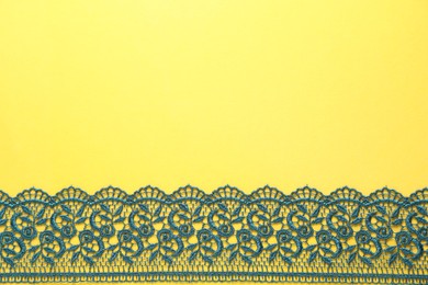 Photo of Green lace on yellow background, top view. Space for text