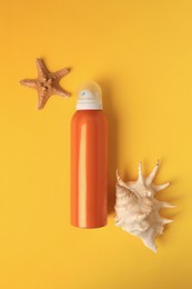 Bottle of sunscreen, starfish and seashell on yellow background, flat lay