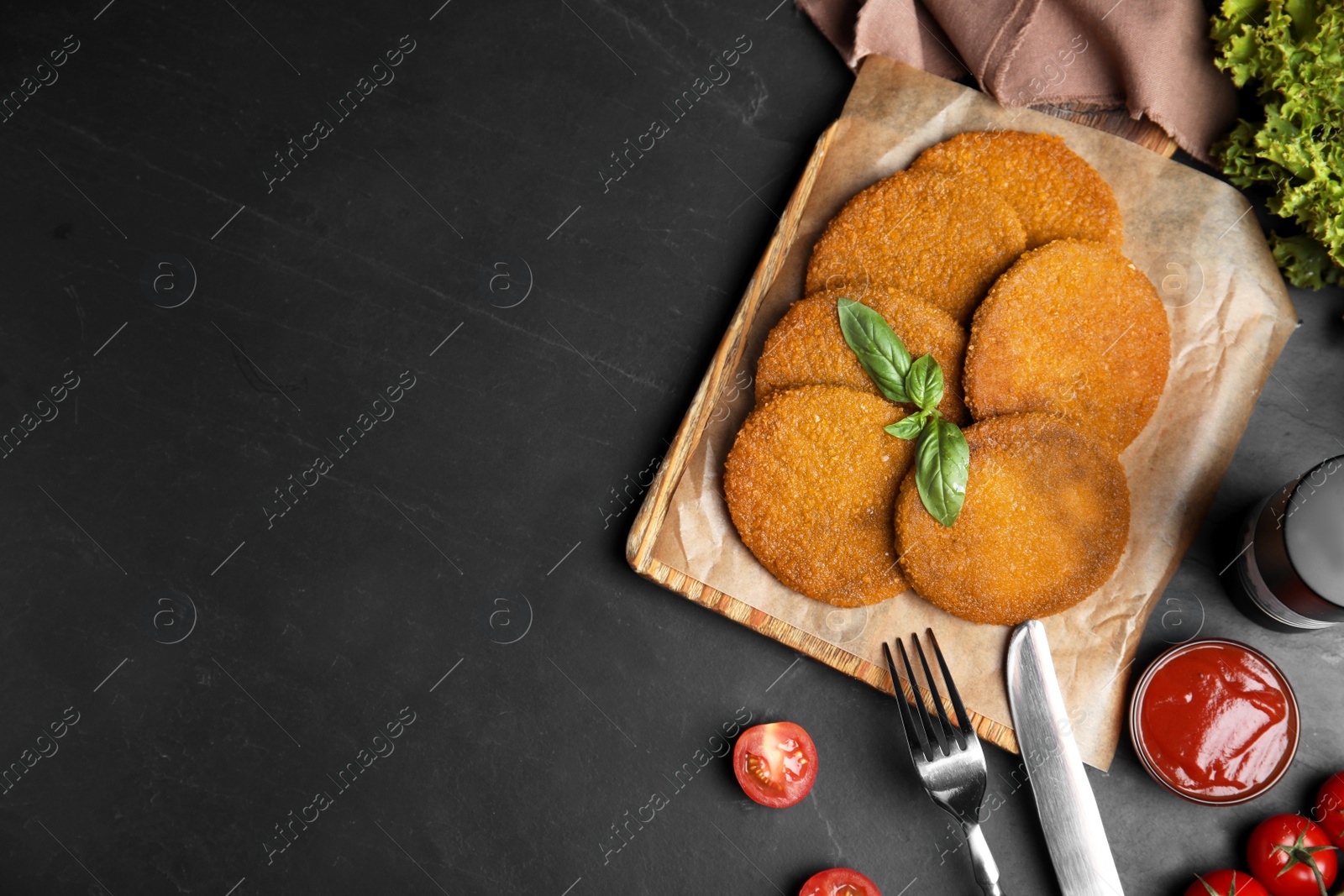 Photo of Delicious fried breaded cutlets served on black table, flat lay. Space for text