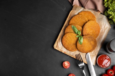 Photo of Delicious fried breaded cutlets served on black table, flat lay. Space for text