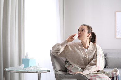 Photo of Sick young woman using nasal spray at home