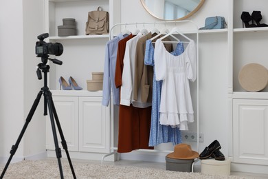 Photo of Fashion blogger's workplace. Shoes, clothes, camera and stylish furniture indoors