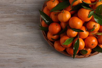 Photo of Fresh ripe juicy tangerines and green leaves on white wooden table, top view. Space for text
