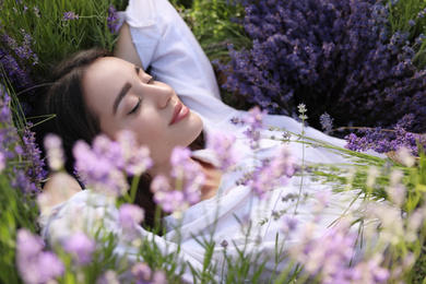 Photo of Young woman lying in lavender field on summer day