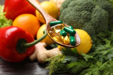 Photo of Dietary supplements. Spoon with pills over food products, closeup