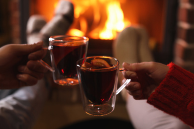 Photo of Couple with mulled wine near fireplace indoors, closeup. Winter vacation