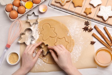 Photo of Woman making Christmas cookies with cutters at white wooden table, top view
