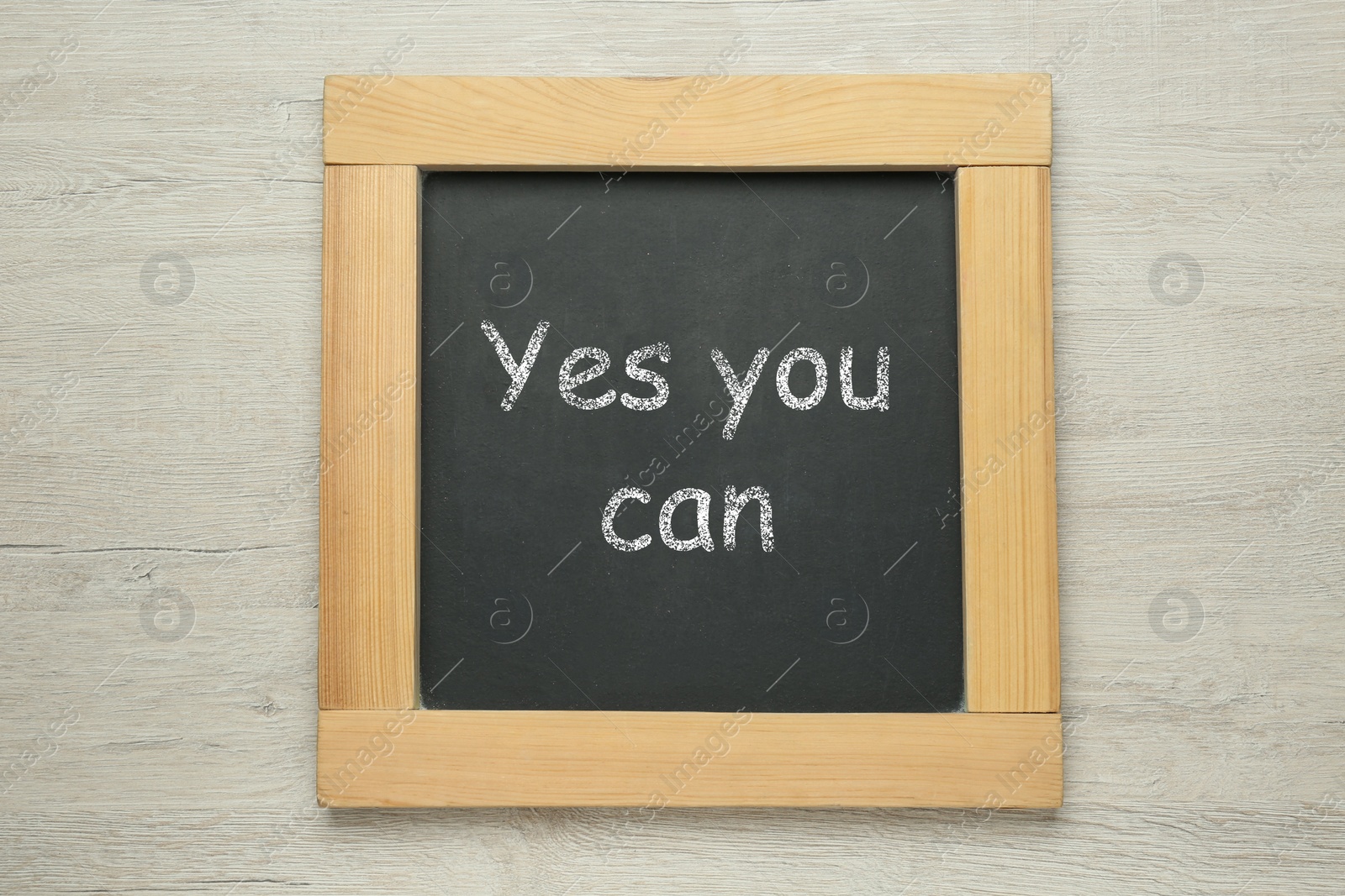 Photo of Small chalkboard with motivational quote Yes you can on white wooden background, top view