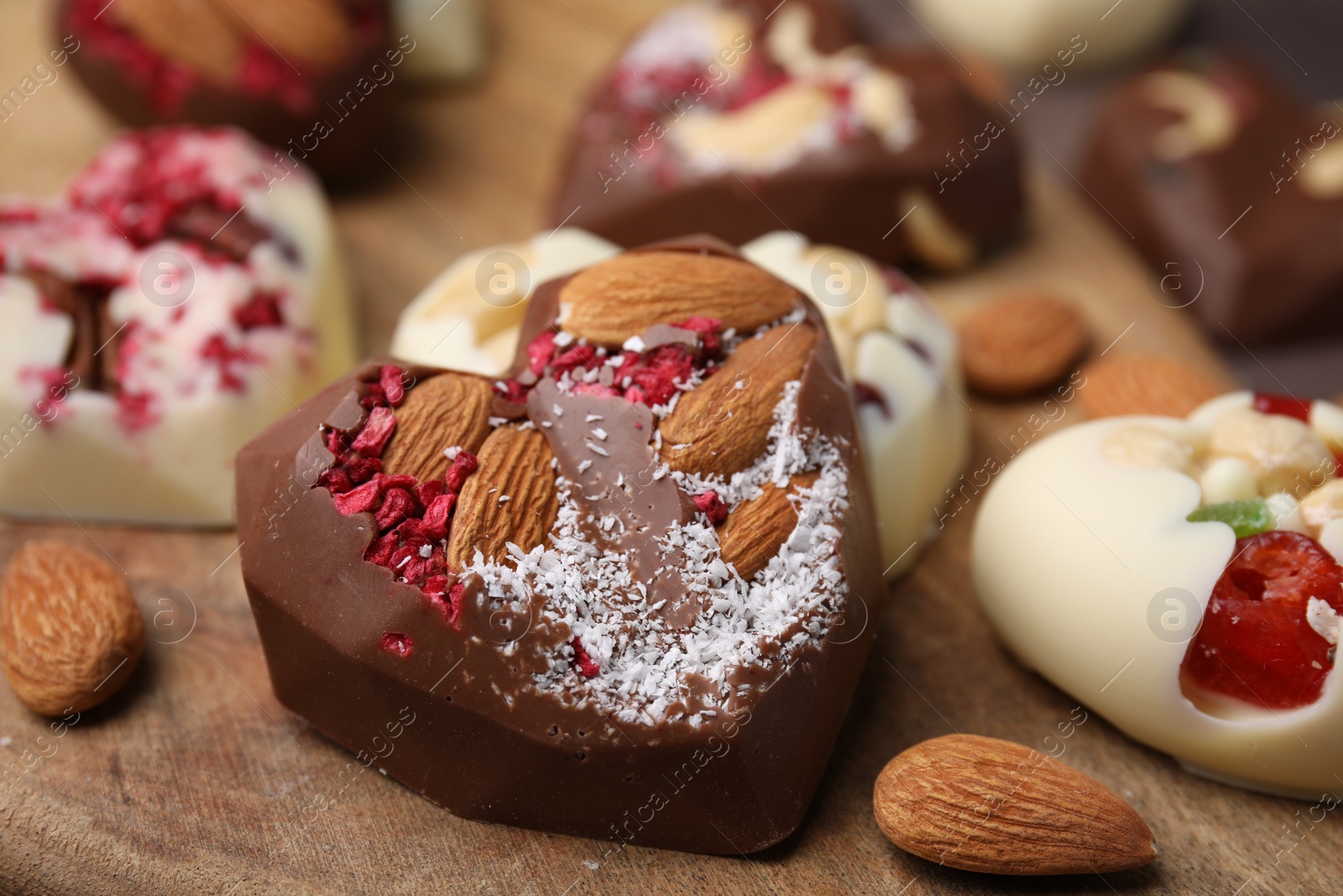 Photo of Tasty chocolate heart shaped candies with nuts, closeup