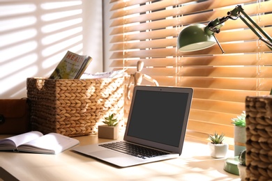 Comfortable workplace with laptop near window at home