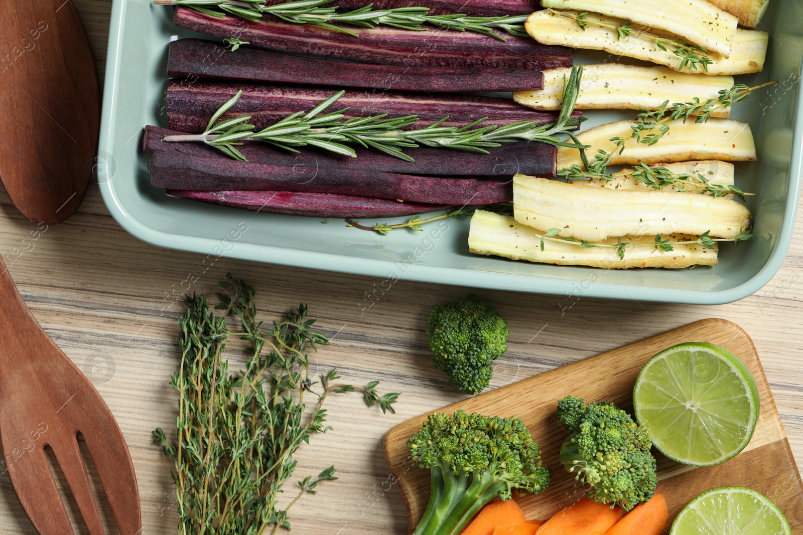 Photo of Flat lay composition with raw cut carrots in baking dish on wooden table
